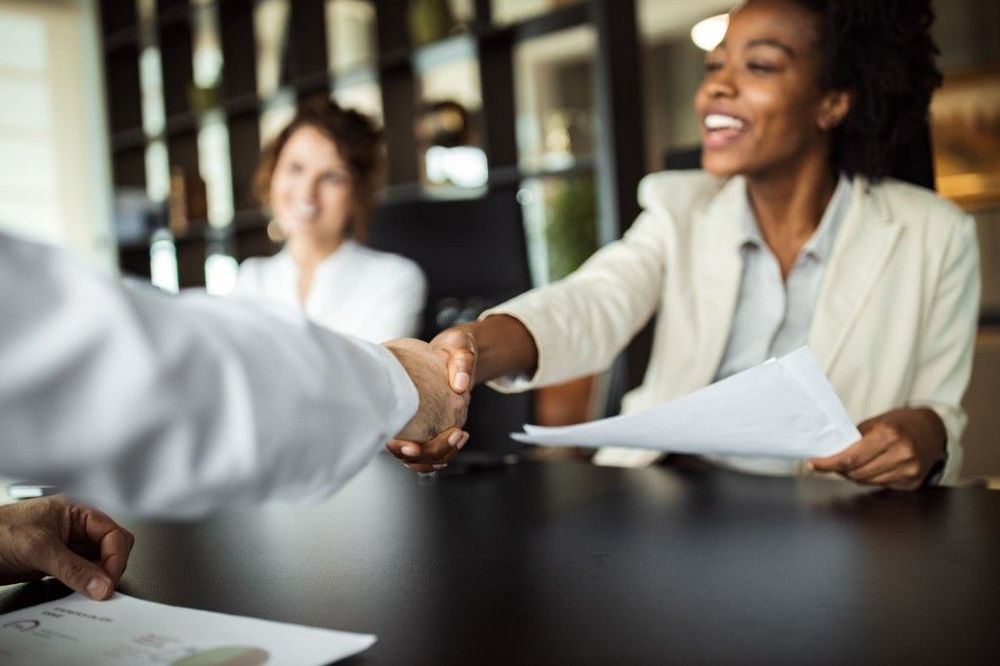 A woman shaking hands across a table