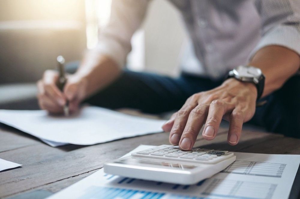 A man working with a calculator and financial paperwork.