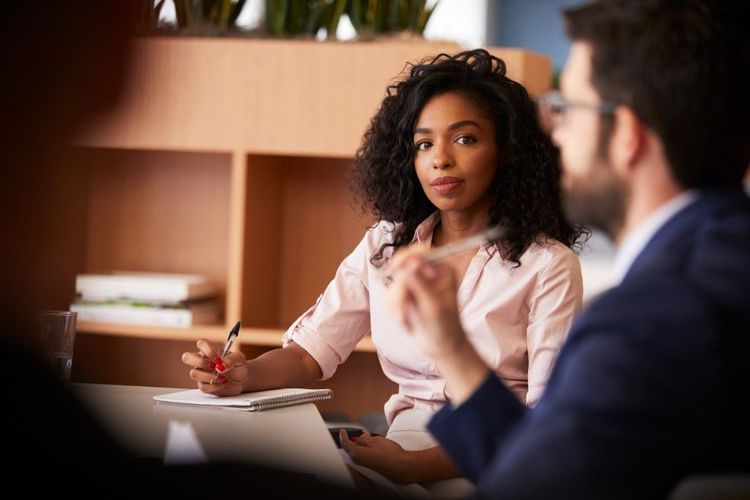 A Black woman taking notes during a professional meeting