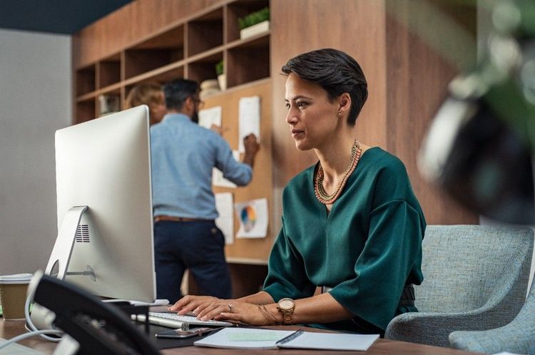 A business owner focused on her computer in a busy office