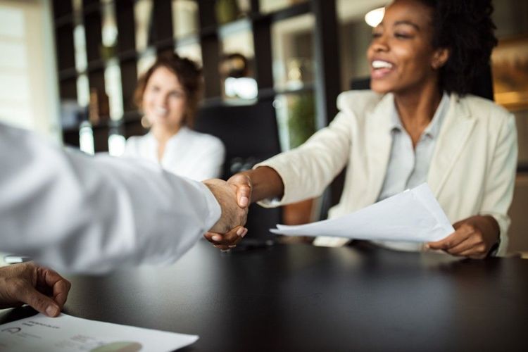 A woman shaking hands across a table