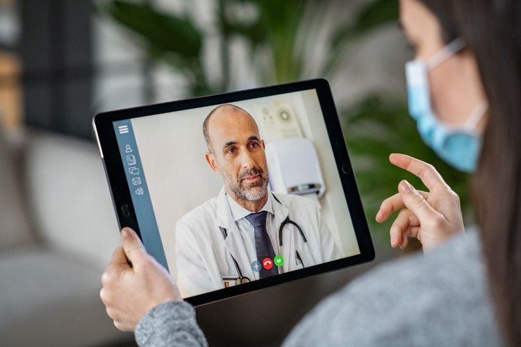 A patient on a video call with a doctor in a white coat