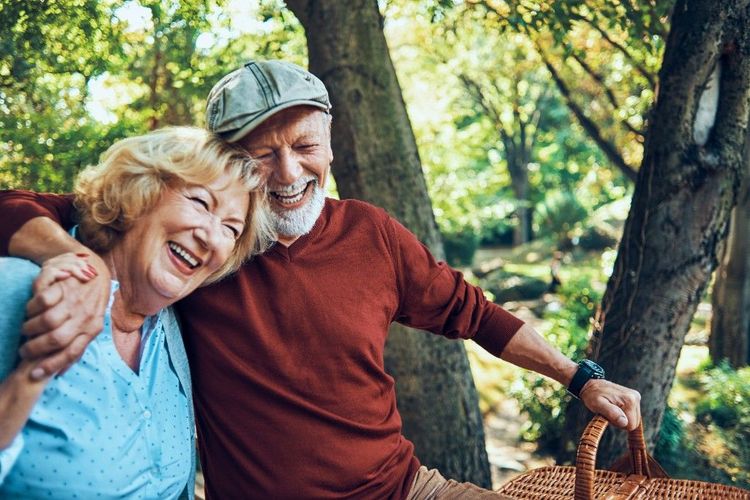 A smiling senior couple laughing together outdoors in a park