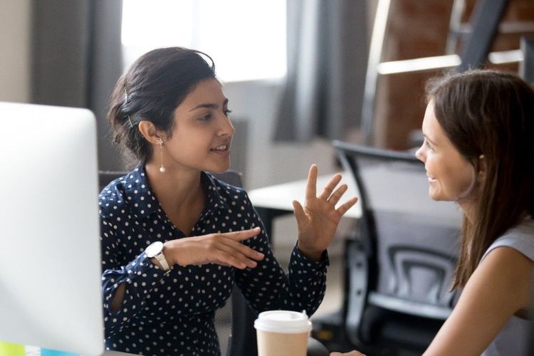 Two colleagues collaborating at a desk in a bright office